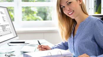 Young Businesswoman Calculating Bill With Computer And Laptop On Desk